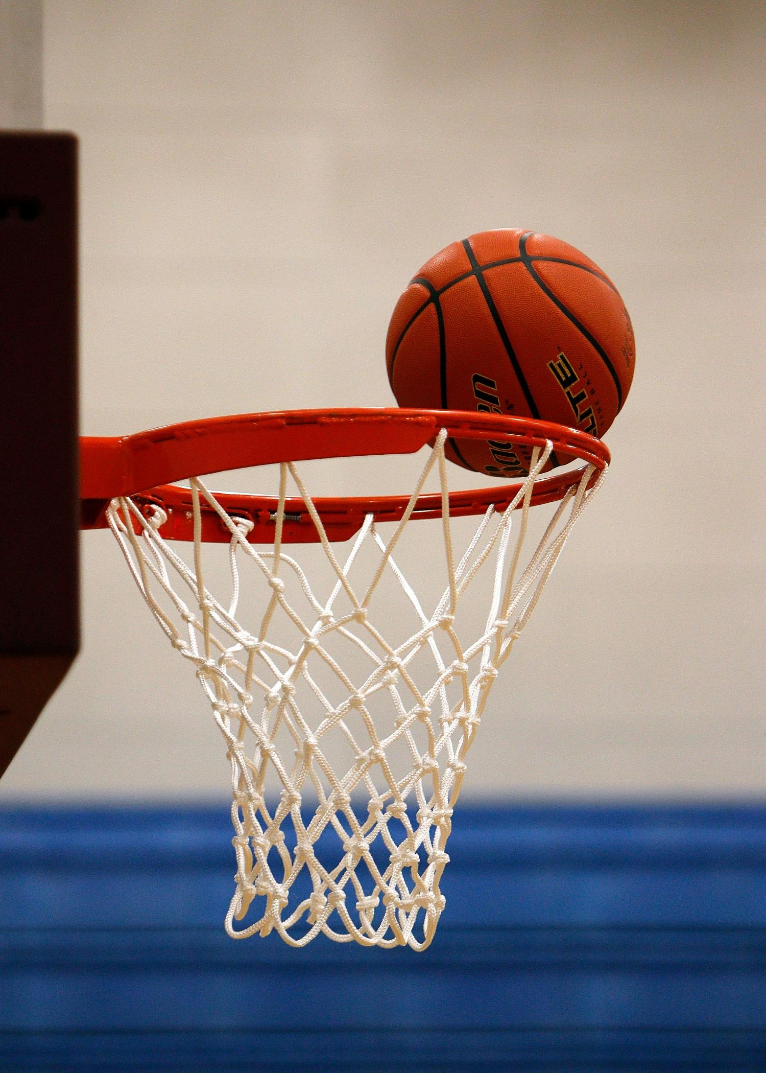 Un ballon de basket au-dessus de l’arceau et du filet.